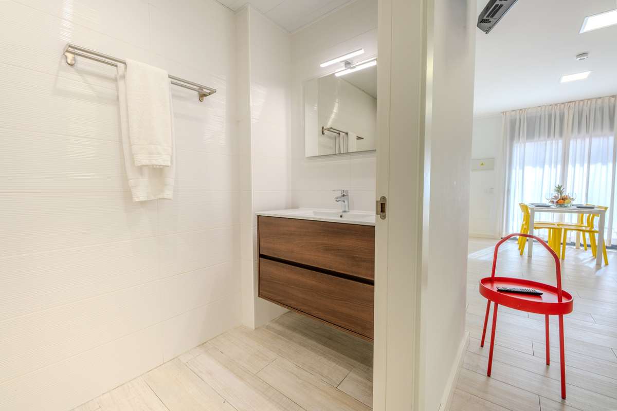 Baño y, al fondo, el salón del apartamento de un dormitorio superior del Castell Beach Aparthotel