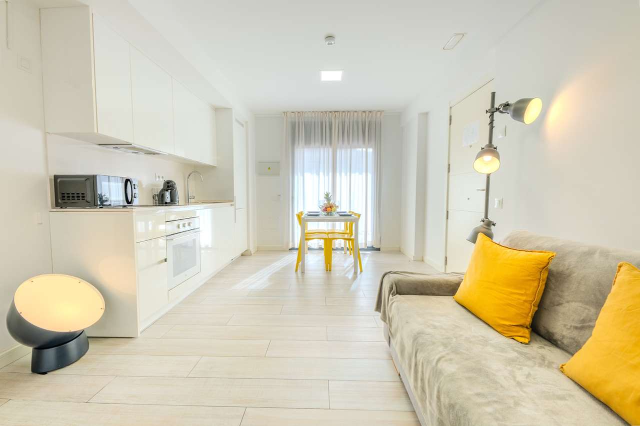 Salón amplio y luminoso del apartamento de un dormitorio superior, con cocina y sofá