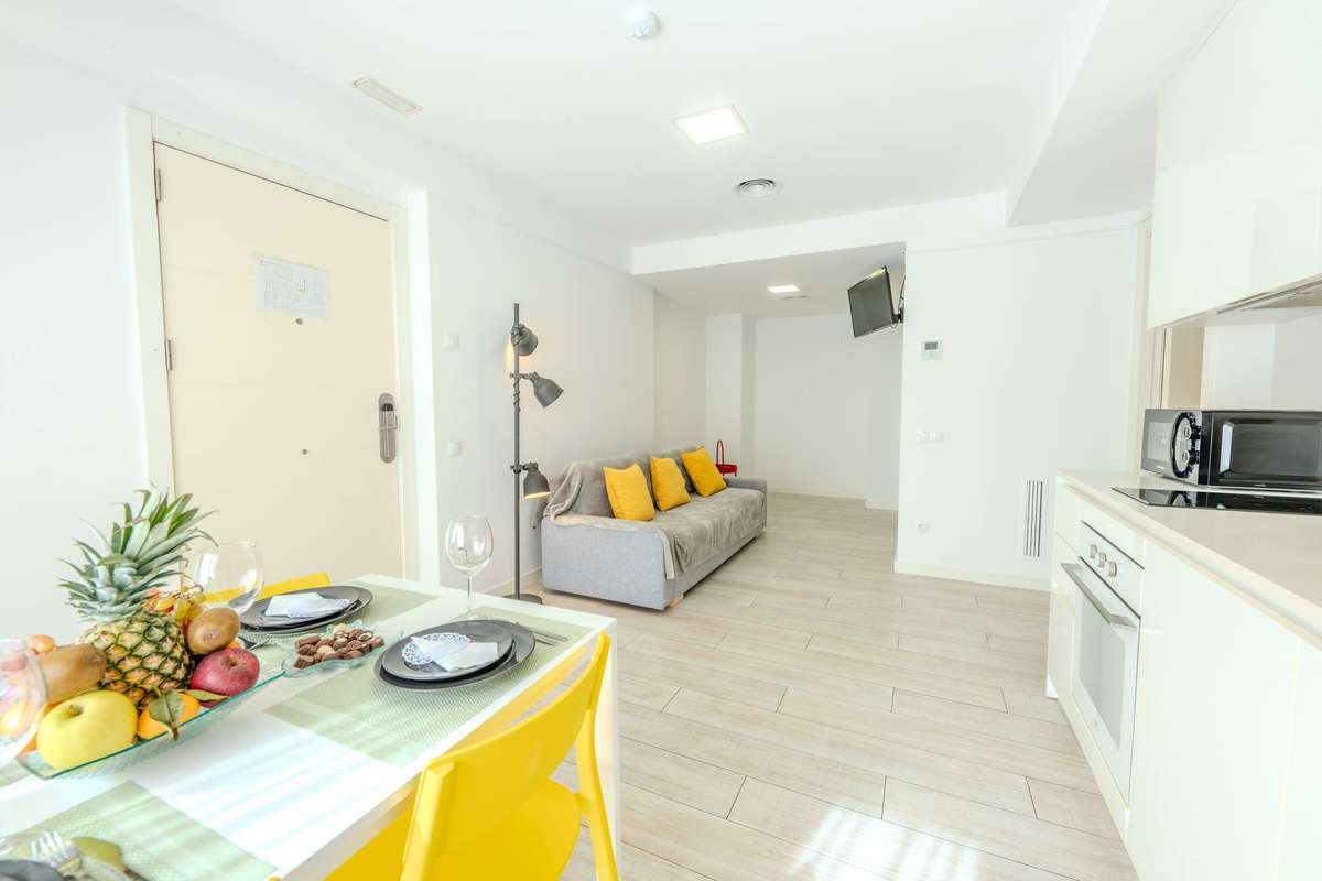 Comedor con la mesa puesta y salón del apartamento de un dormitorio superior del Castell Beach Aparthotel