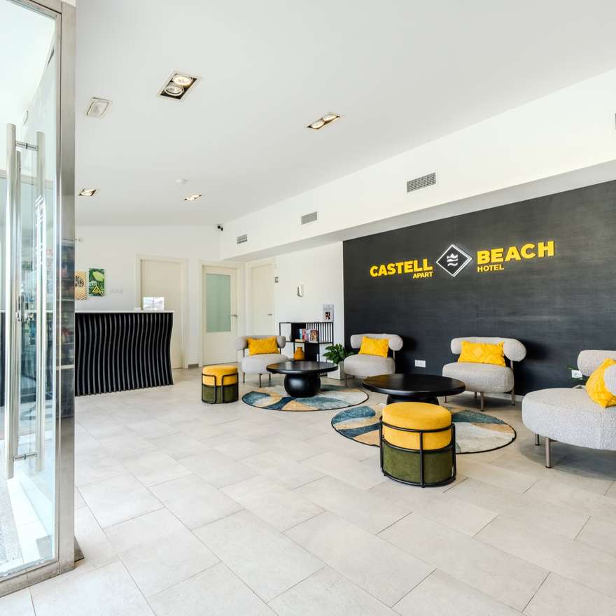 Recepción del Castell Beach Aparthotel en Castelldefels, con zona de espera y el logo del hotel