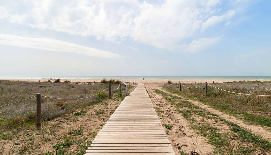Pasarela de madera entre las dunas hacia la playa