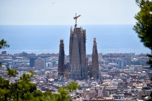 La Sagrada Familia sobresale entre los edificios de Barcelona, con el mar al fondo, vista desde el Park Güell
