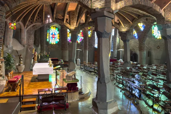 Interior de la Cripta Gaudí de la Colònia Güell, con sus columnas inclinadas, bóvedas de ladrillo y vidrieras de colores