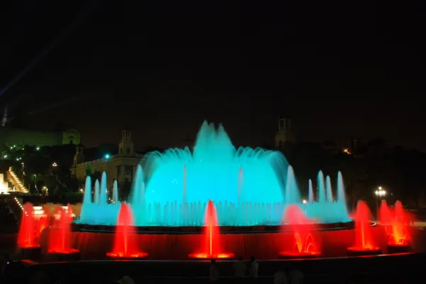 La Font Màgica de Montjuïc de noche, con los chorros iluminados en turquesa y rojo